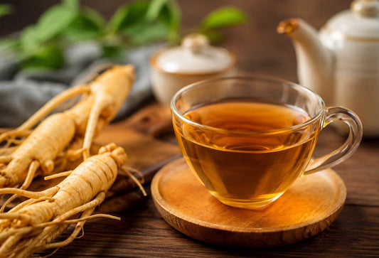 A cup of ginseng tea sitting on a saucer beside some ginseng roots