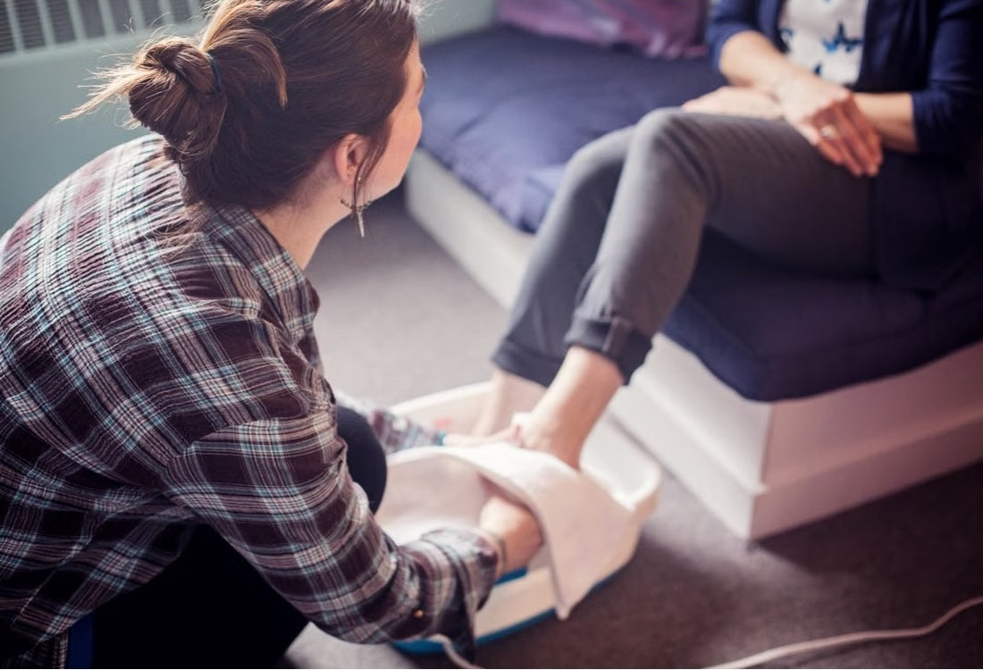 A person provides a calming foot spa treatment in a cozy indoor salon setting to another person