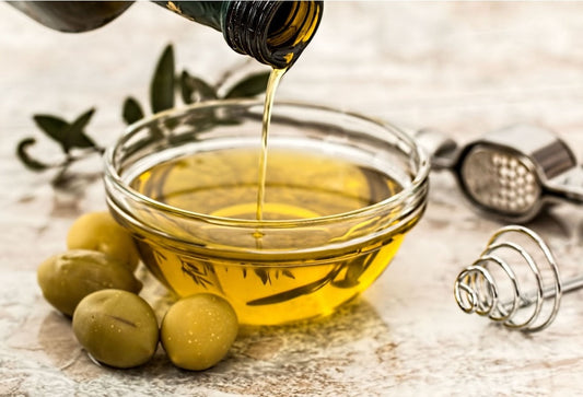 Bowl of olive oil with fresh olives at the side