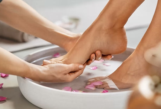 Therapist supporting a client's foot in a rose petal foot bath, demonstrating an ionic detox session